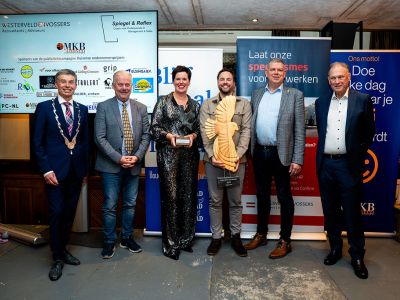 winnaars staan omringd door jury en burgemeester met hun prijzen in de hand.